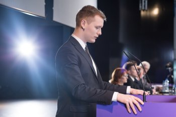 Mann steht an Pult und hält Rede