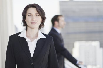 Frau  im Anzug im Vordergrund, im Hintergrund Business-Szene