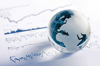 Weltkugel aus Glas liegt auf Wirtschaftspapieren.