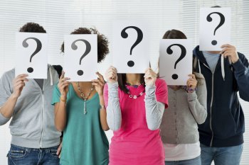 Menschen verstecken ihre Gesichter hinter Schildern, auf denen ein Fragezeichen ist