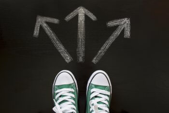 Füße stehen vor drei Pfeilen, die in andere Richtungen zeigen