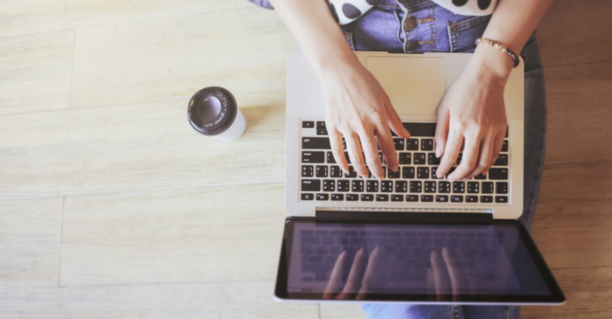 Blick von oben auf die Beine einer Studentin mit Laptop auf dem Schoß
