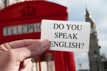 Englische Telefonzelle im Hintergrund, vorne hält jemand eine Karte mit der Frage Do you speak English?